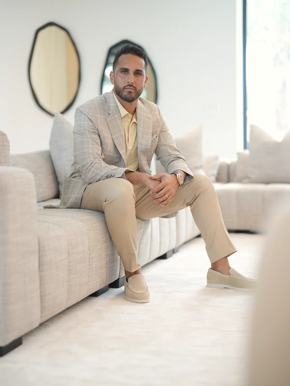 Firenze: the light check sport jacket, beige chinos, a pale yellow polo and beige suede loafers, seated on a sofa