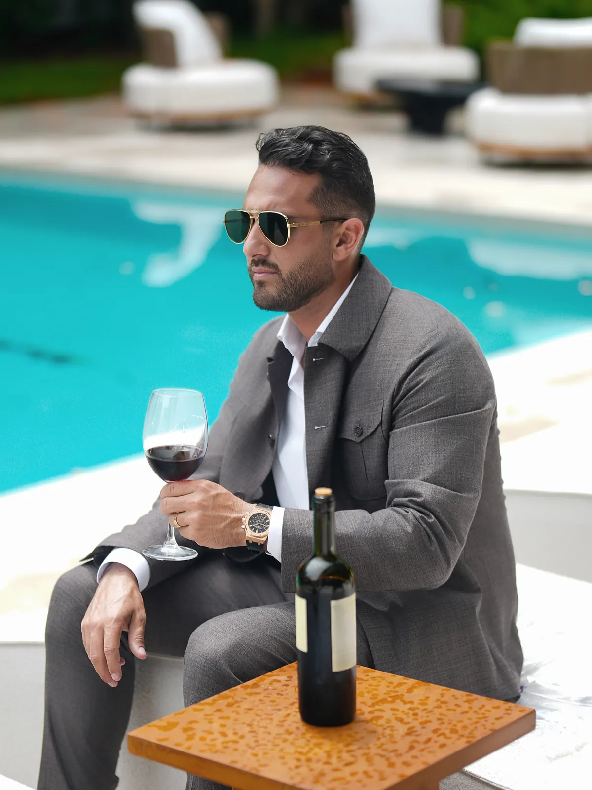 Roma: the brown jacket with chest pockets and matching trousers, seated by a pool