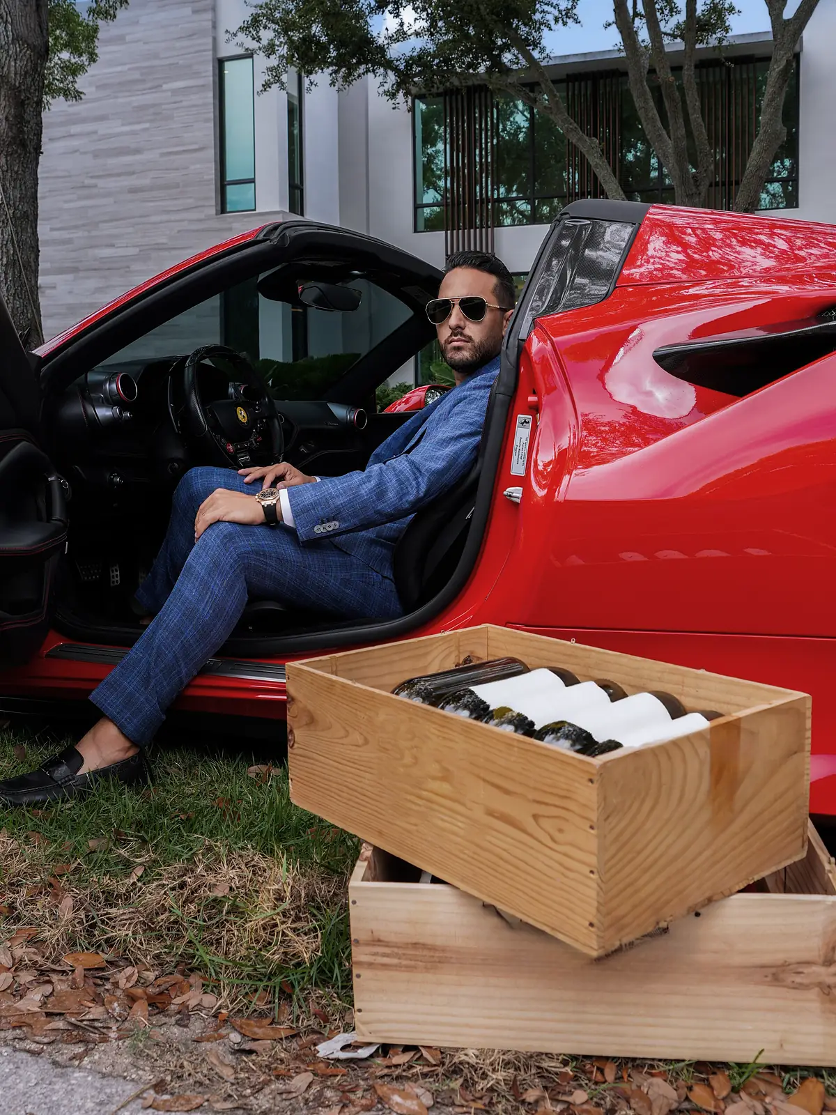 Torino: the blue windowpane suit, seated in the open door of a red Ferrari