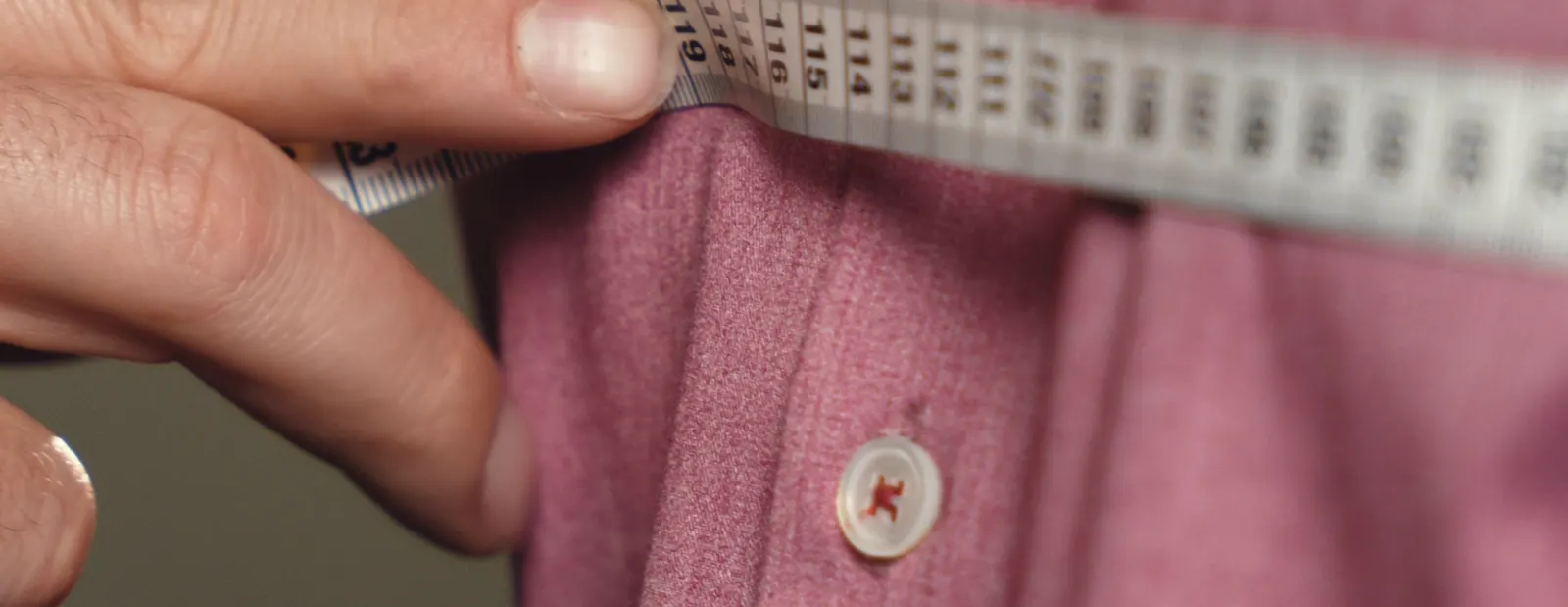 A tape measure held against a garment during a fitting