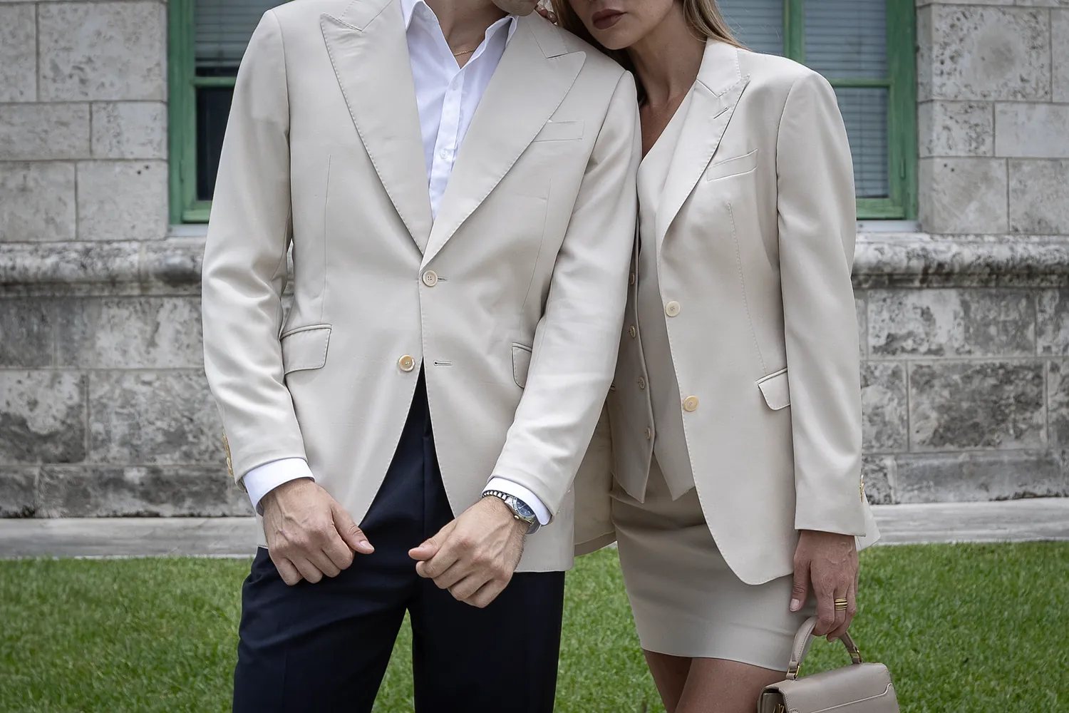 Two cream jackets side by side outside Coral Gables City Hall, his over navy trousers, hers over a matching waistcoat and skirt
