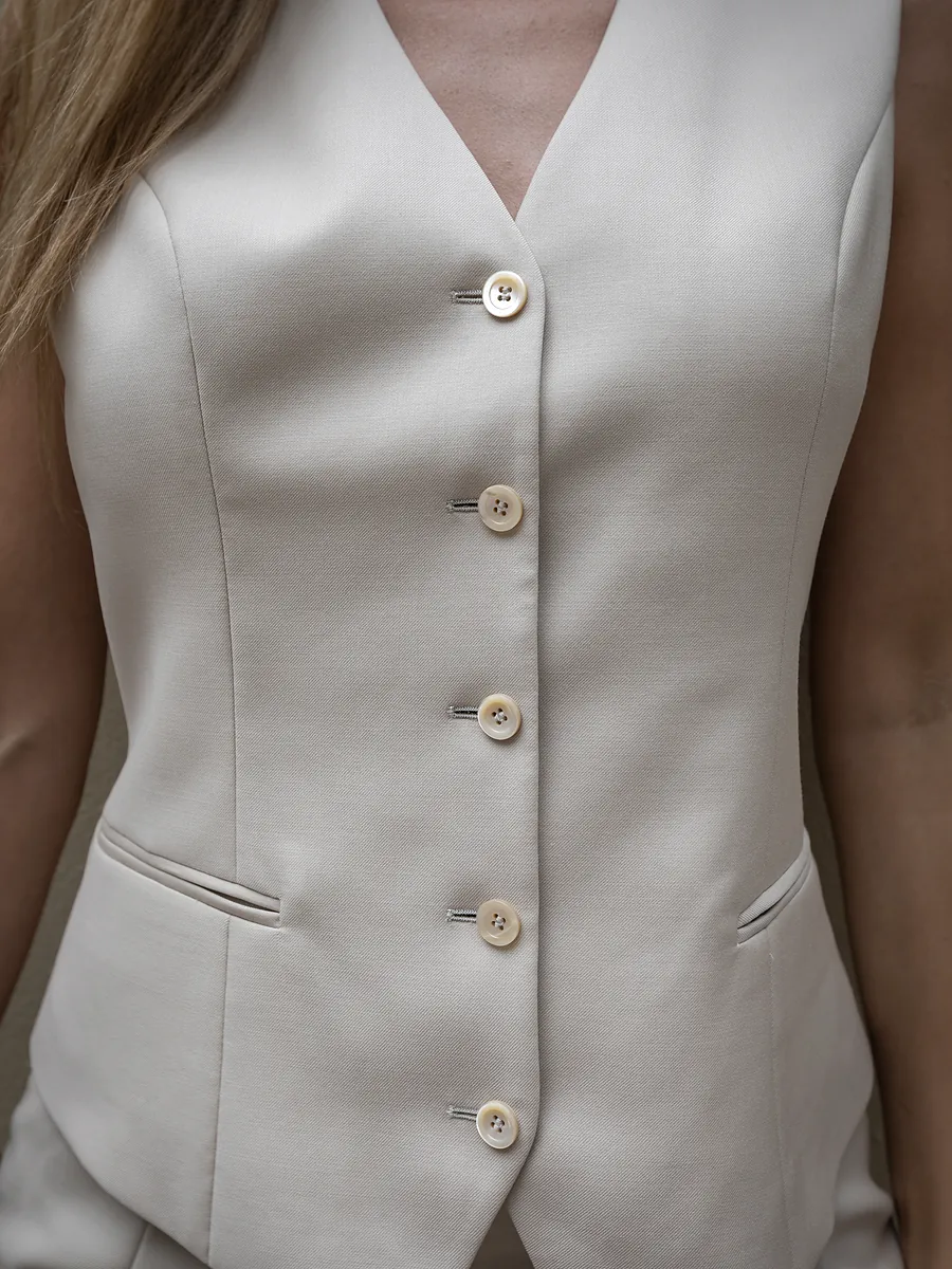 Close view of the cream five-button waistcoat as she wears it